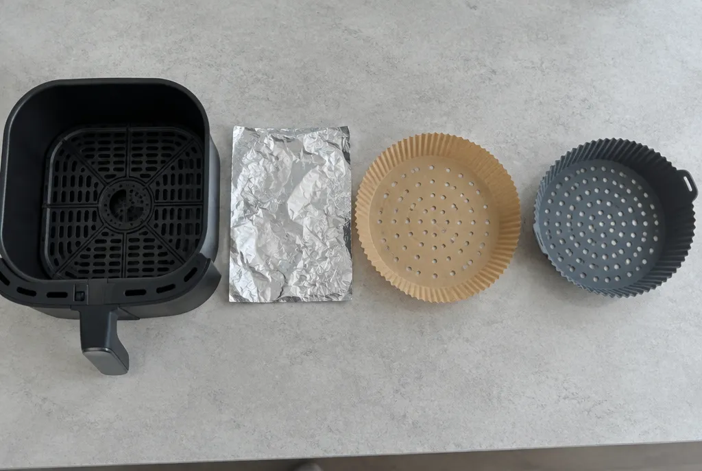 Air fryer basket lined with a perforated paper liner holding chicken thighs
