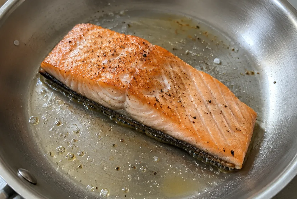 Salmon fillet searing skin-side down in a stainless steel pan